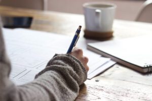 someone writing at a desk with coffee