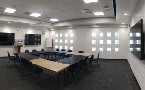 Townhall Square C conference room set up with seating for 14 and 3 wall-mounted TVs.