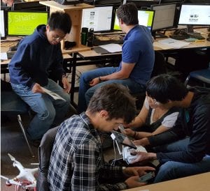 Four students in a classroom with two drones