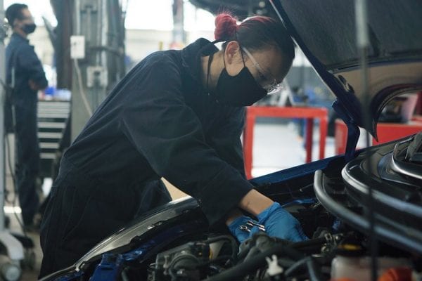 BCIT student wearing mask working under the hood of a car