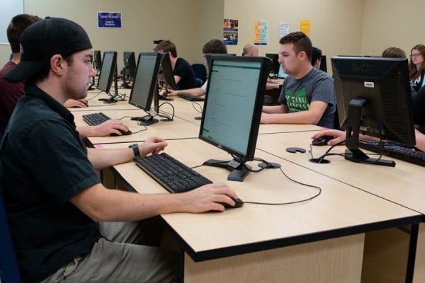 People sitting and working at computers during a trades entry assessment.