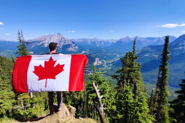 Person holding Canada flag with mountain scenery