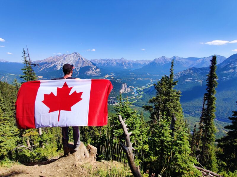 Person holding Canada flag with mountain scenery