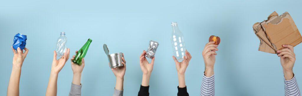 Image of Many hands with different types of garbage on color background.