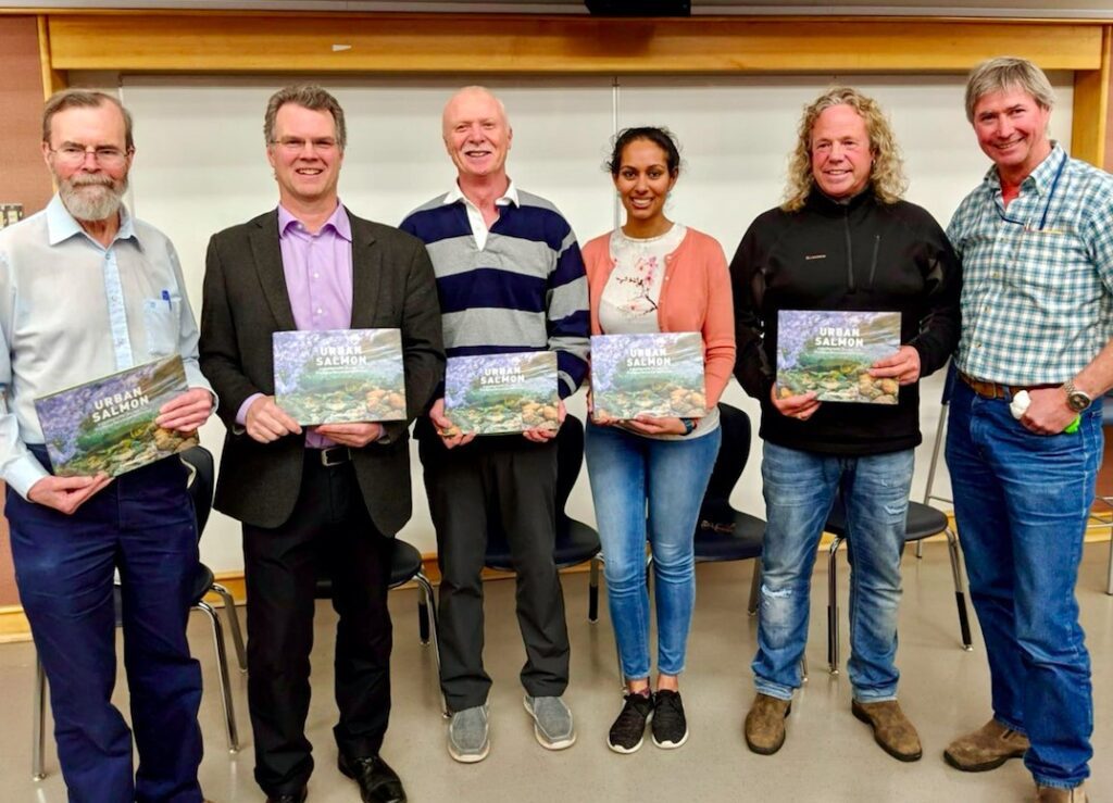 six people standing in a line each holding a book
