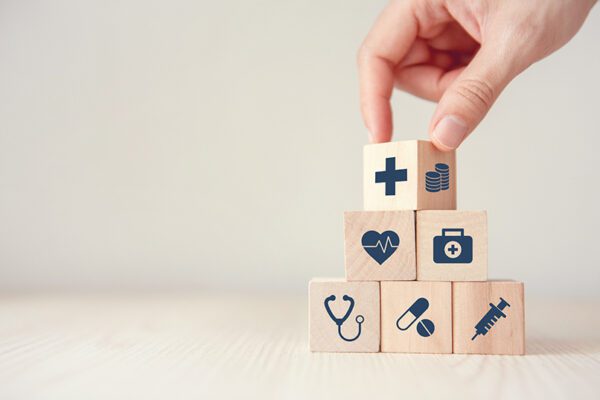 Health Insurance Concept, Hand arranging wood cube stacking with icon healthcare medical on wood background, copy space, financial concept.