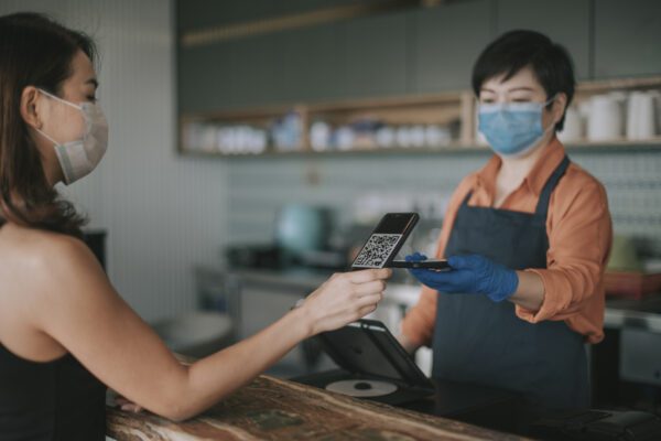 an asian chinese cafe owner businesswoman receiving payment from her customer at counter using QR code contactless payment