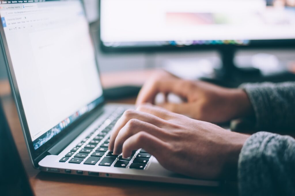 a person's hands typing on a laptop