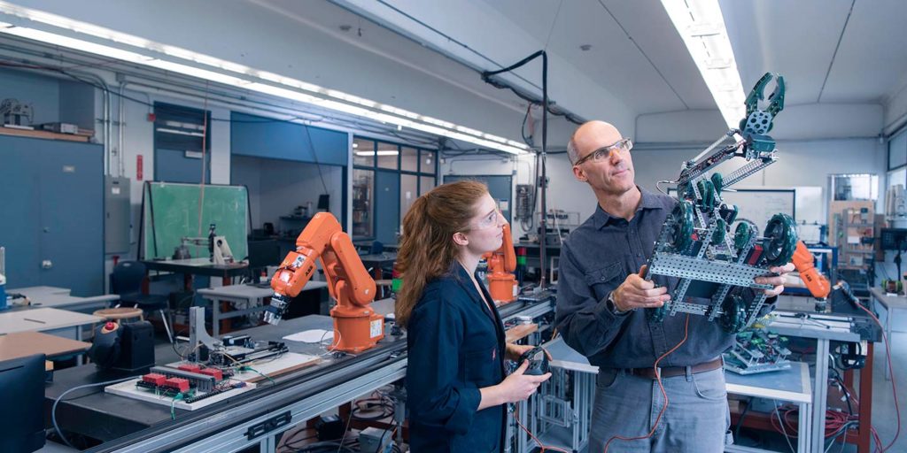 instructor with a student holding a robot in a lab