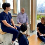 patient partner Bill sitting on stairs with 3 health sciences students