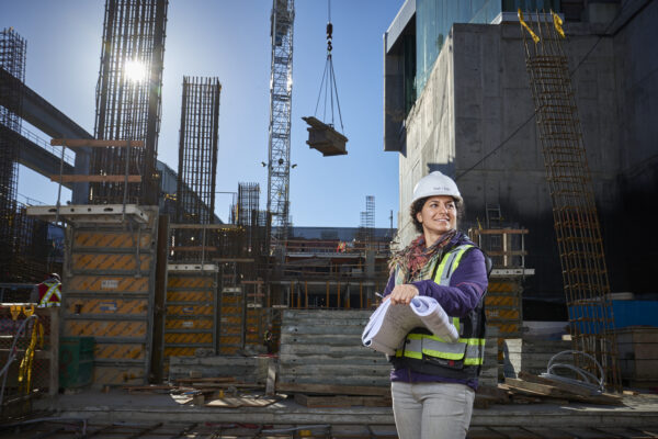 Female engineer wearing a hard hat stands on a construction site