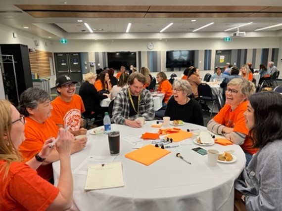 People in orange shirts gathered around a table