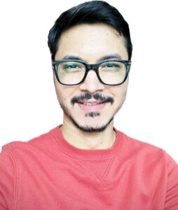 Image of a man from the chest up wearing glasses wearing a red shirt.