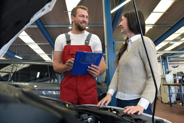 Kundendienst in der Autowerkstatt - Mechaniker und Kundin bespre