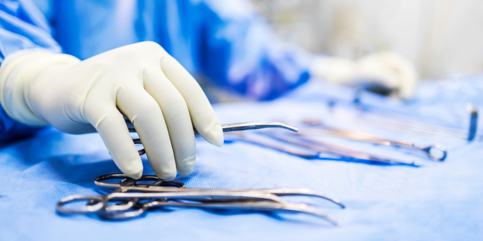 medical professional picks up instrument off of sterile field tray