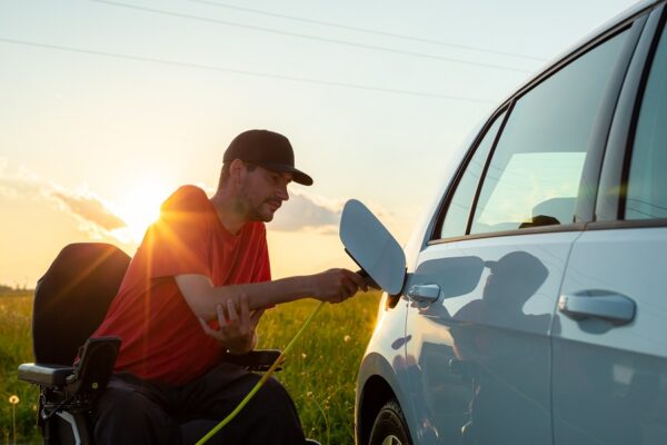 Man in a wheelchair charging an electric car