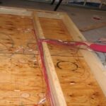 Wood-frame wall test panel lying on floor with sensor cables attached