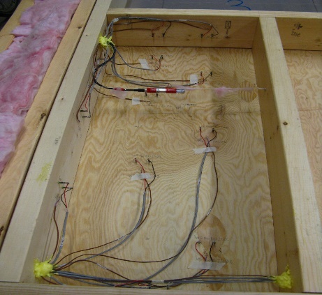 Wood-frame test panel lying on floor with sensor cables attached