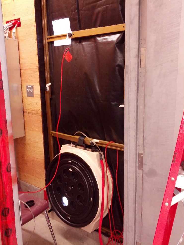 A blower door used for envelope air-tightness testing installed within a doorframe