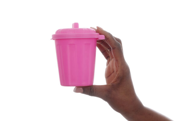 Hand holding a tiny pink garbage can.