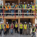 The full cohort of MaTT Hub Associate Certificate students pose together on the completed two-storey mass timber mock-up structure at BCIT's Burnaby campus.