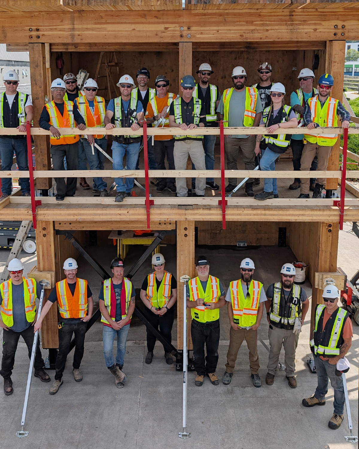 The full cohort of MaTT Hub Associate Certificate students pose together on the completed two-storey mass timber mock-up structure at BCIT's Burnaby campus.