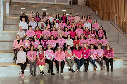 A group of faculty and staff in pink shirts.