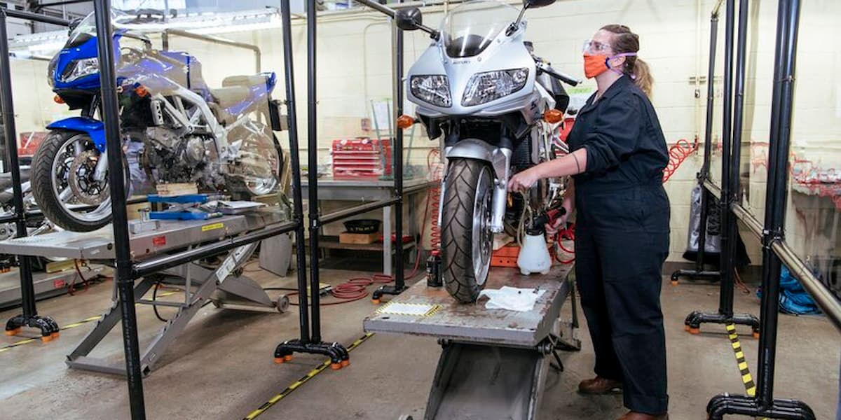 A Motorcycle Technician Foundation student tunes up a motorbike on a hoist in the BCIT mechanic shop.