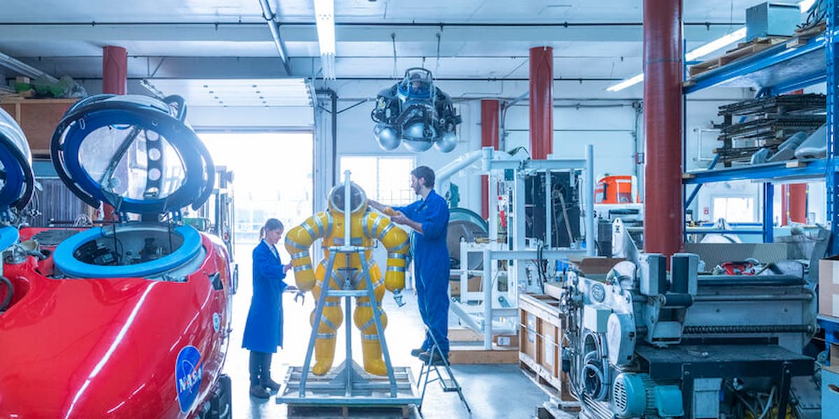 Students use experiential learning to explore a space suit in a warehouse at a BCIT learning facility.
