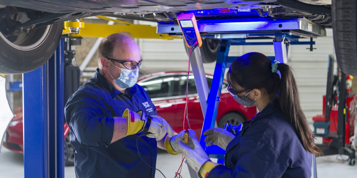 Two people work on an EV