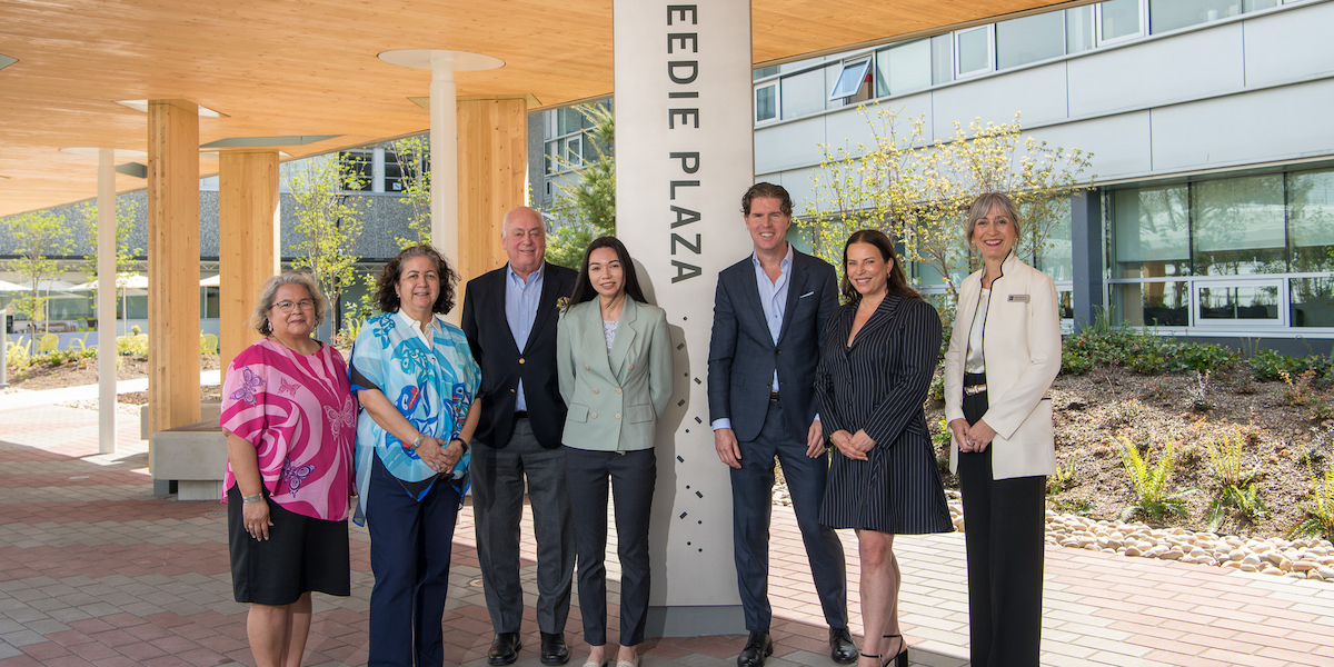 Seven people gather around the Beedie Plaza pillar to celebrate the unveiling of the new Beedie Plaza at the BCIT Burnaby Campus.
