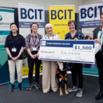 Five people standing in from of three BCIT banners holding a novelty cheque