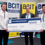 Three people standing in from of three BCIT banners holding a novelty cheque
