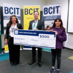 Three people standing in from of three BCIT banners holding a novelty cheque