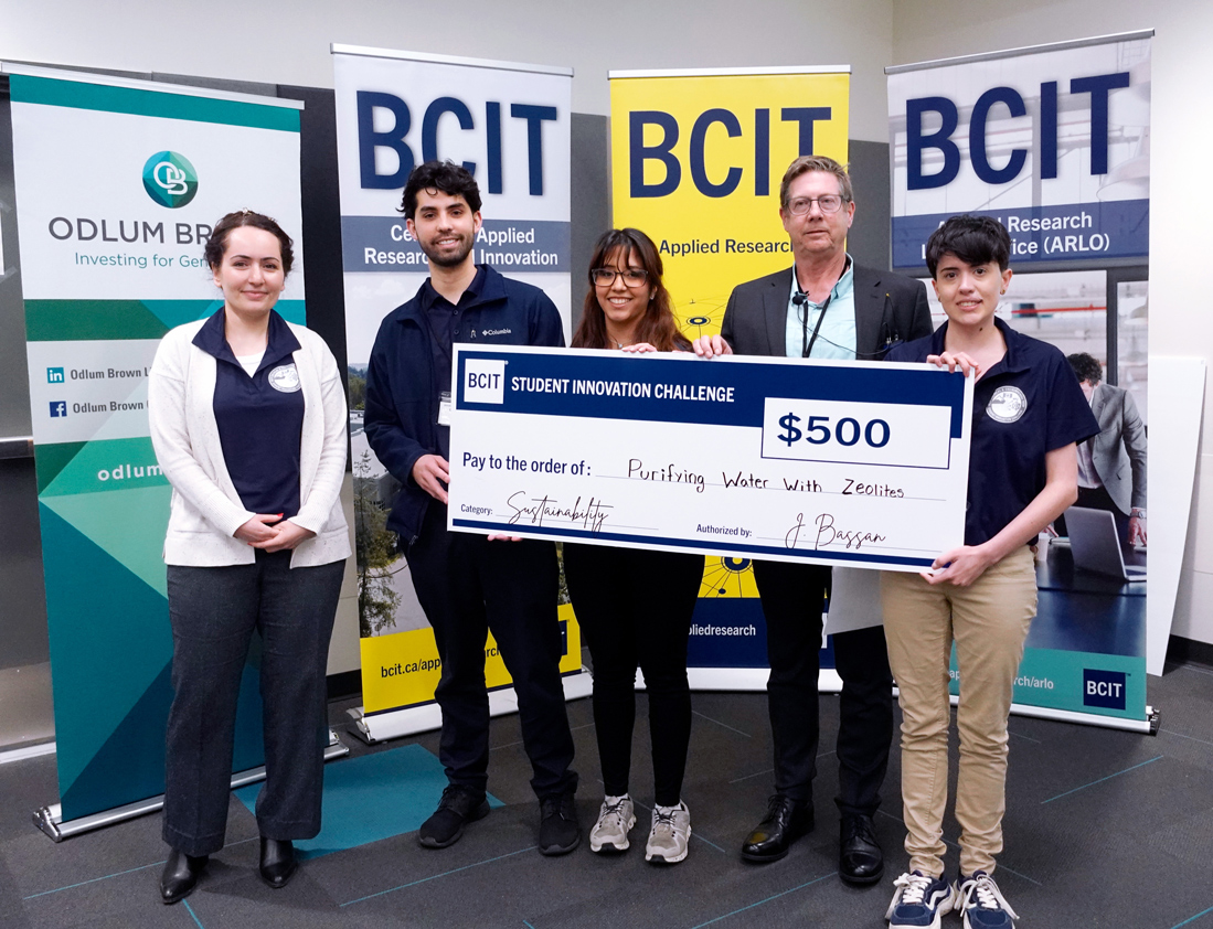 Five people standing in from of three BCIT banners holding a novelty cheque
