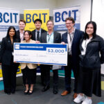 Seven people standing in from of three BCIT banners holding a novelty cheque