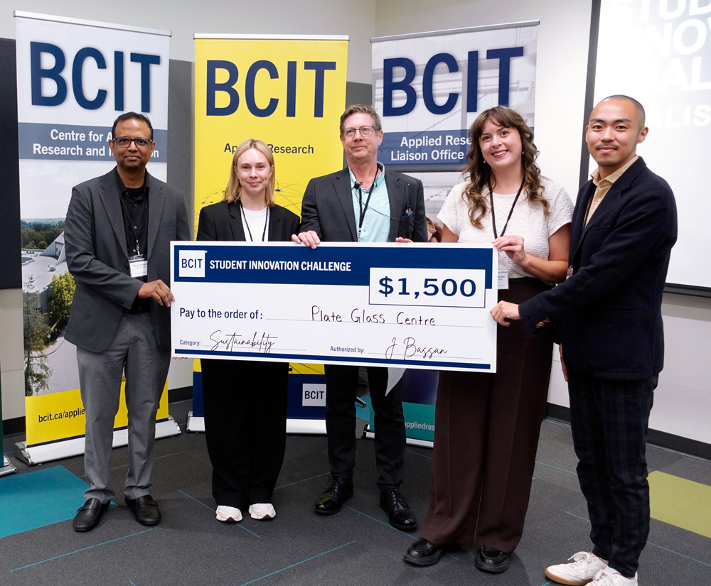 Five people standing in from of three BCIT banners holding a novelty cheque