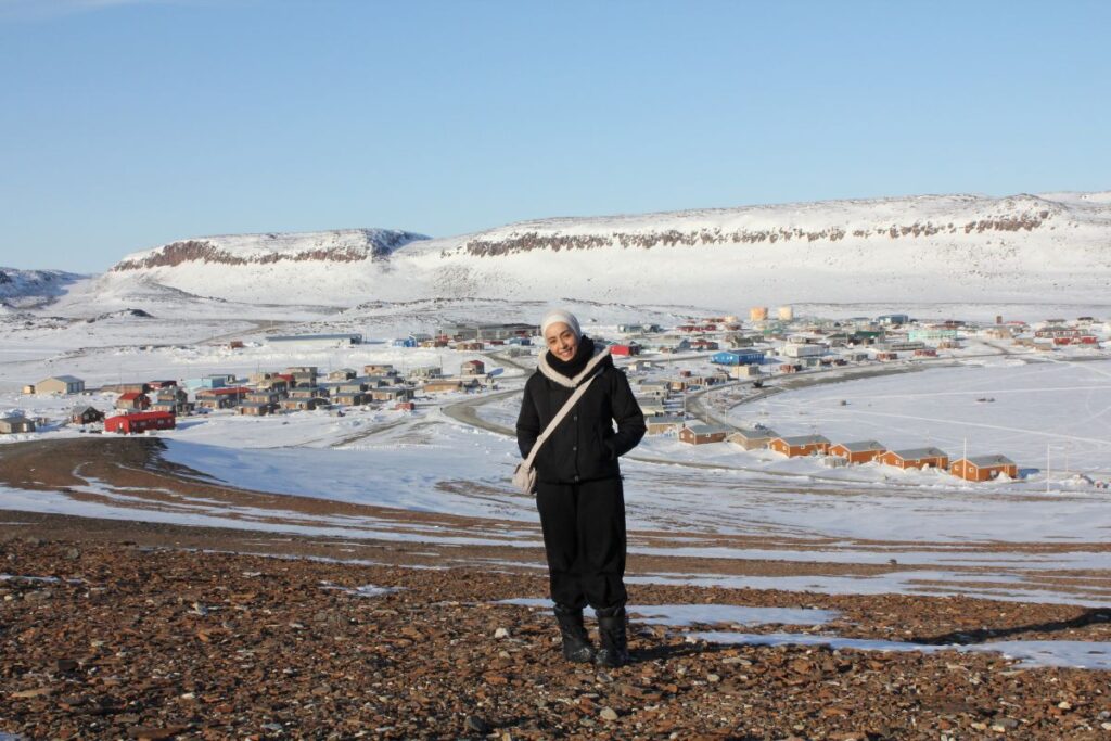 woman stands on a hill above a snowy small village