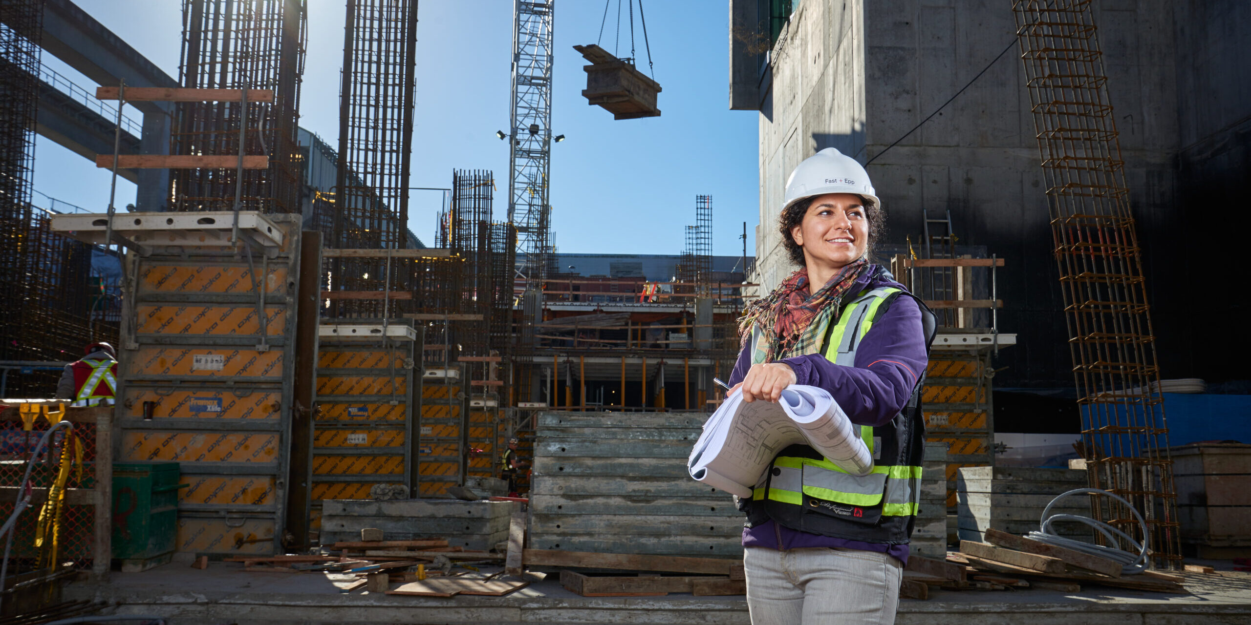 A woman in a hardhat standing in front of a construction site