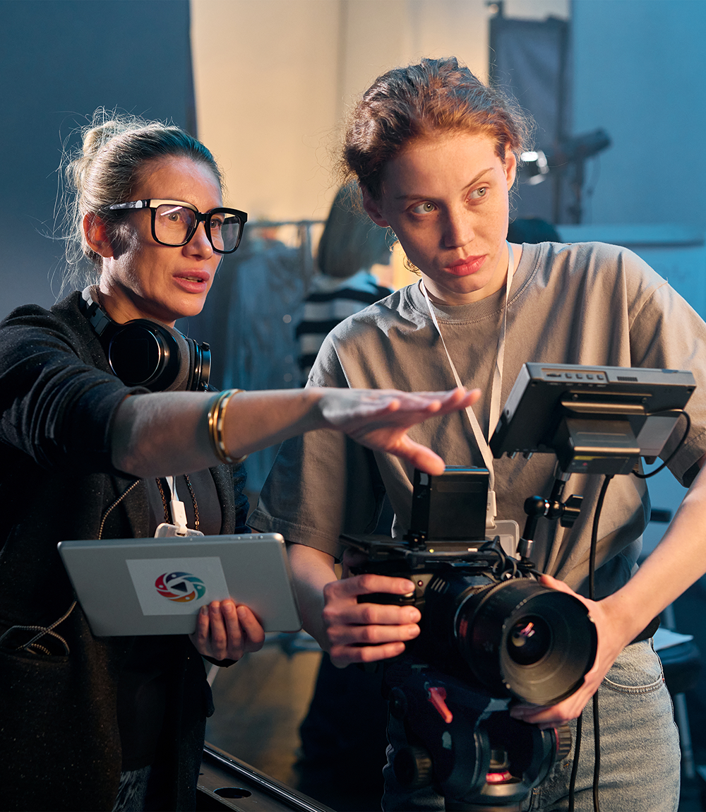 older woman directing younger woman operating video camera
