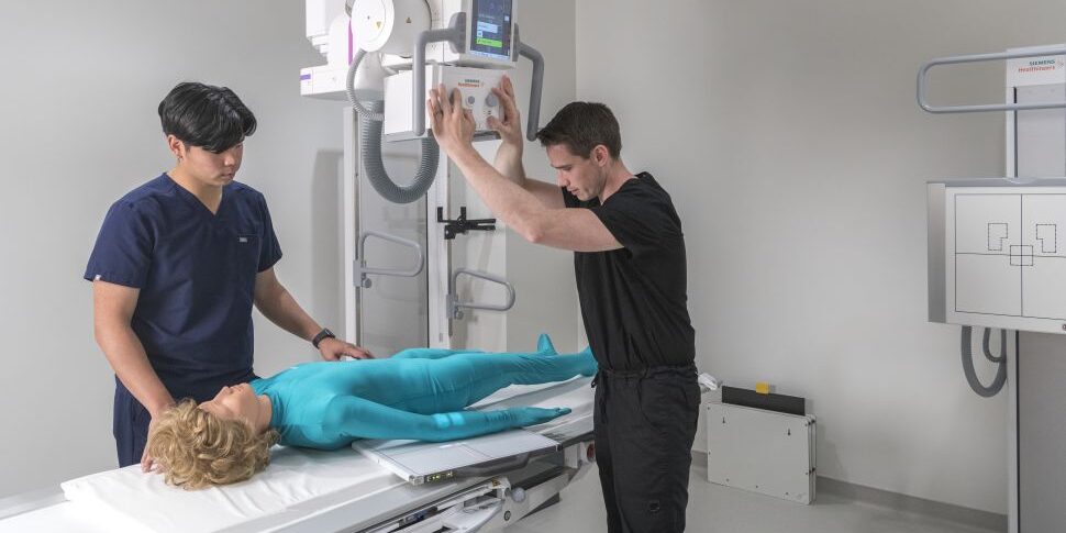 Medical Radiography Instructor and student practice positioning manikin for x-ray