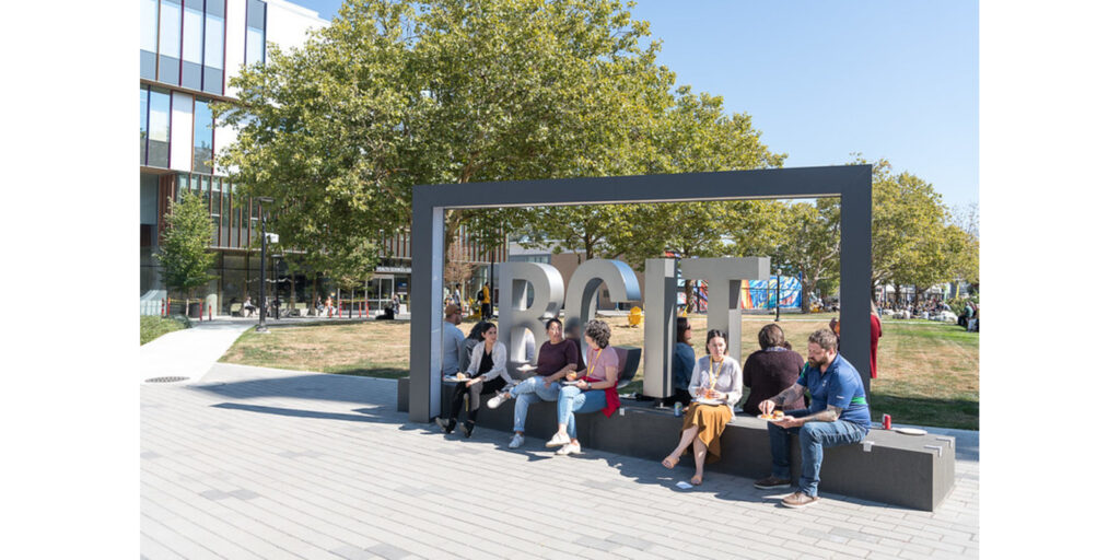 employees at sitting outside by BCIT sign
