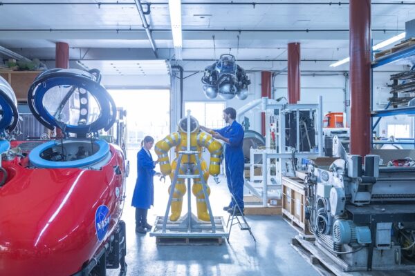 BCIT Electrical Engineering grad works on a submersible body suit in a workshop.