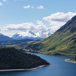 A river next to a mountain with more mountains in the far background.