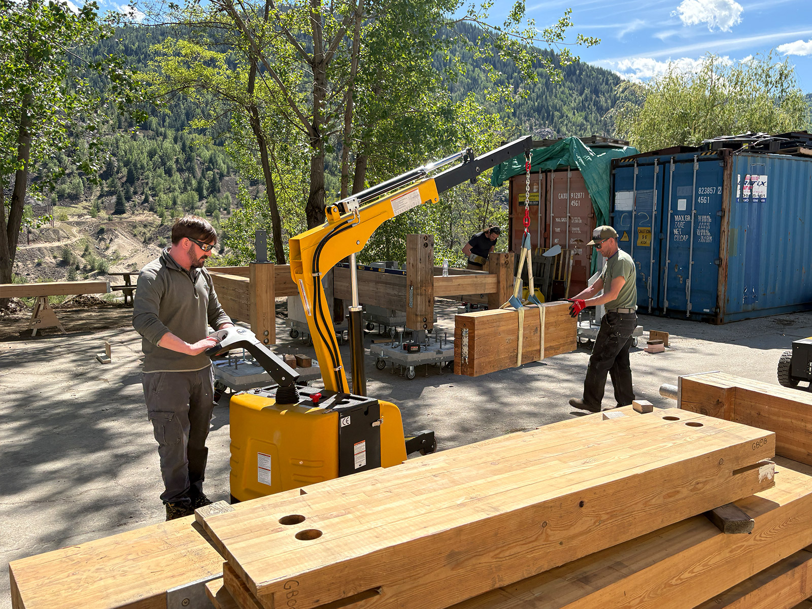 Two people assembling mass timber components using a yellow mobile crane at Selkirk College in the Kootenays, BC.
