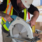 A participant in a BCIT vest using a circular saw to cut a mass timber panel on site.