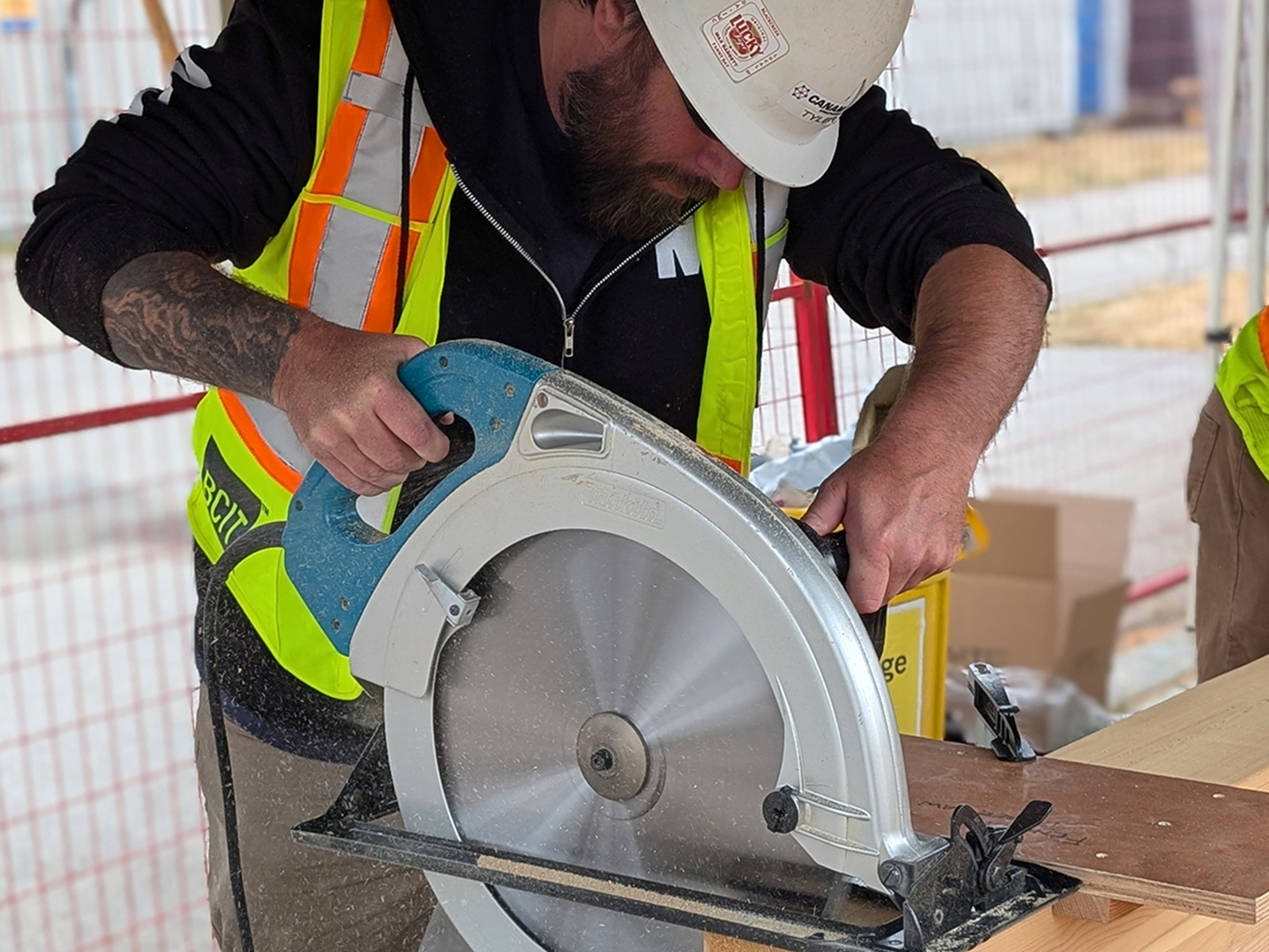 A participant in a BCIT vest using a circular saw to cut a mass timber panel on site.