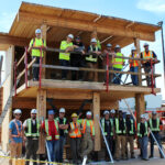 Group photo of practicum participants posing inside and on top of the completed two-storey mass timber structure at BCIT campus.