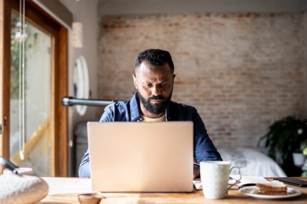 Mature student works on laptop at home to earn a microcredential.